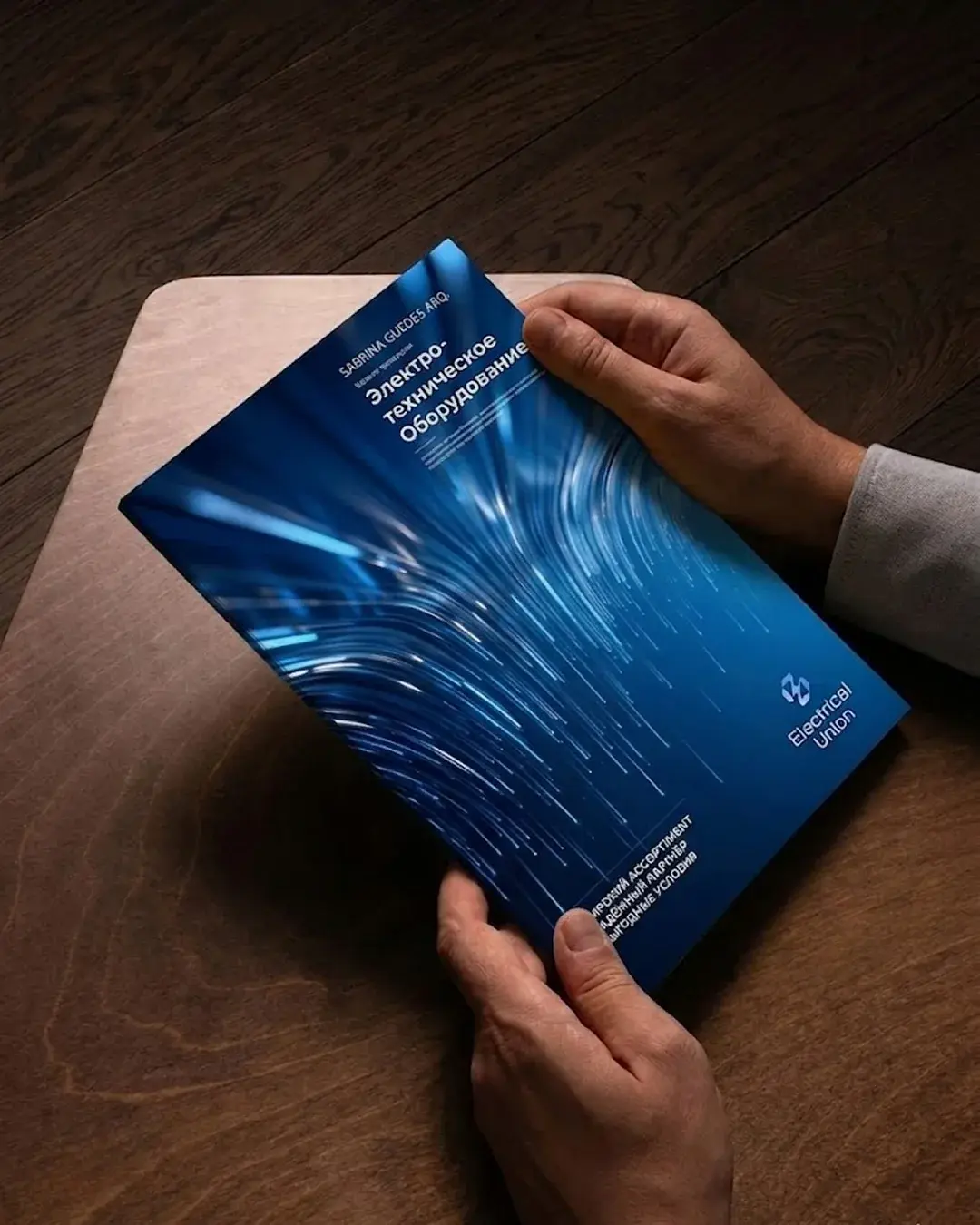 Blue Electrical Union equipment catalogue with a light-streak cover held over a wooden table