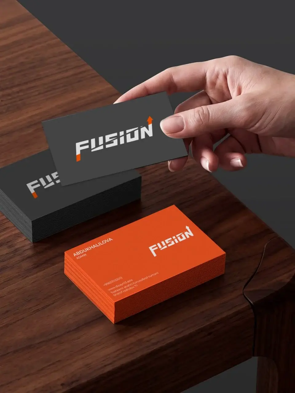 Charcoal and orange Fusion business cards on a walnut table