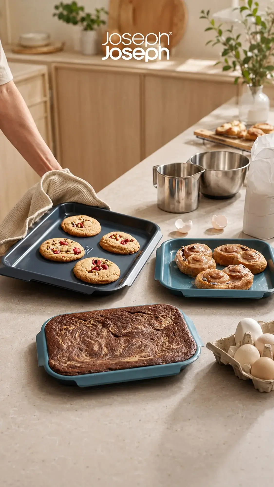 Joseph Joseph nesting bakeware with cookies, pastries and a marble brownie on a stone counter