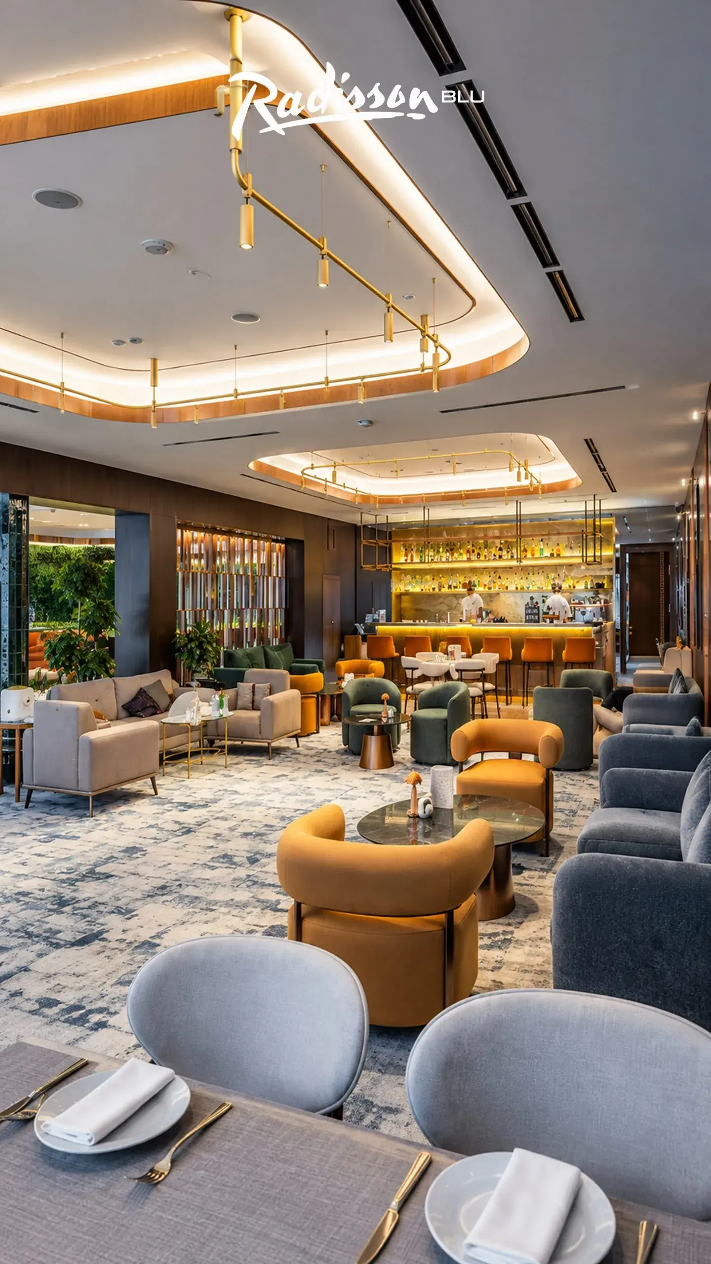 Lobby bar lounge with orange and grey armchairs under brass track lighting