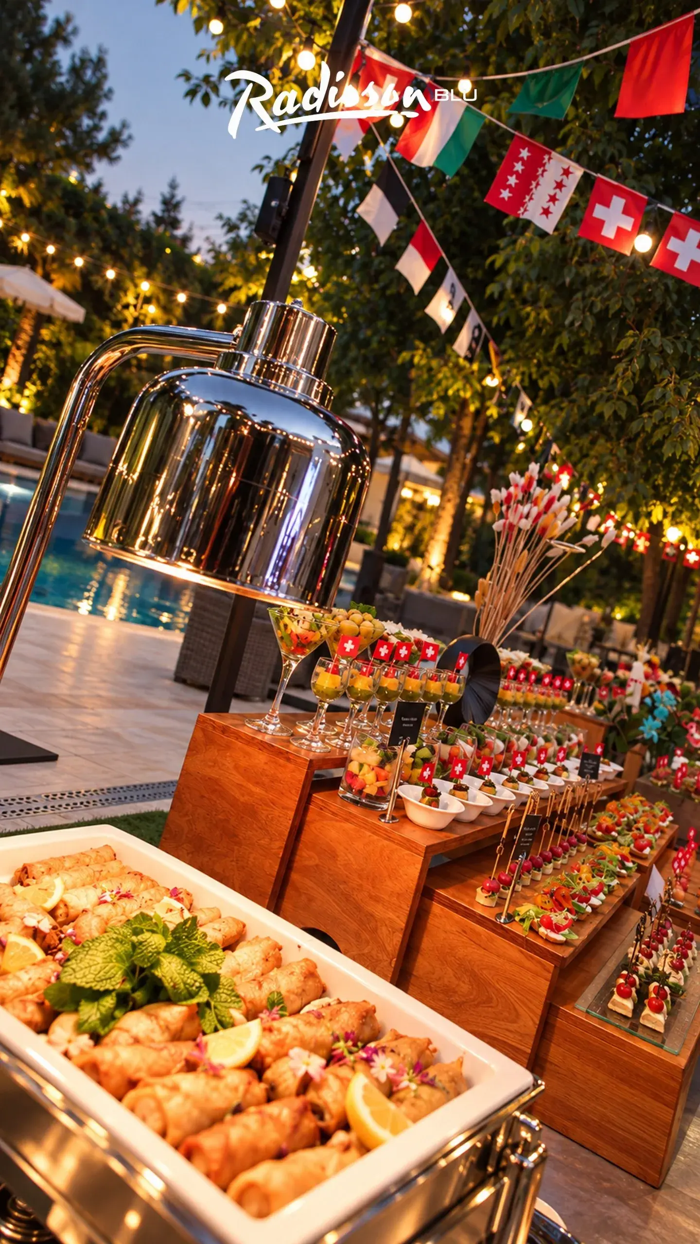 Evening poolside buffet with Swiss flags, string lights and canapés