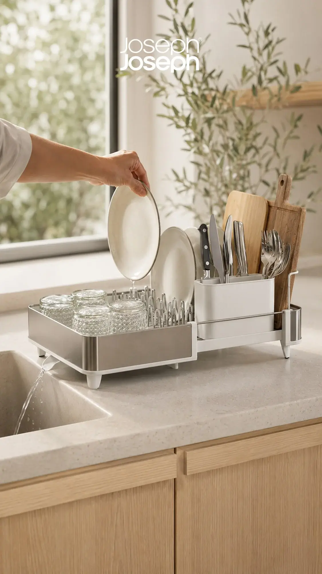 Joseph Joseph extendable dish rack draining into a sink by a sunny window